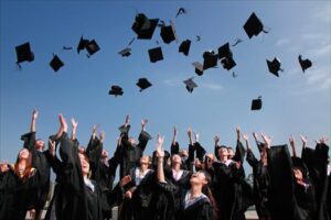 Group of graduates celebrating by throwing caps in the air during a sunny day.